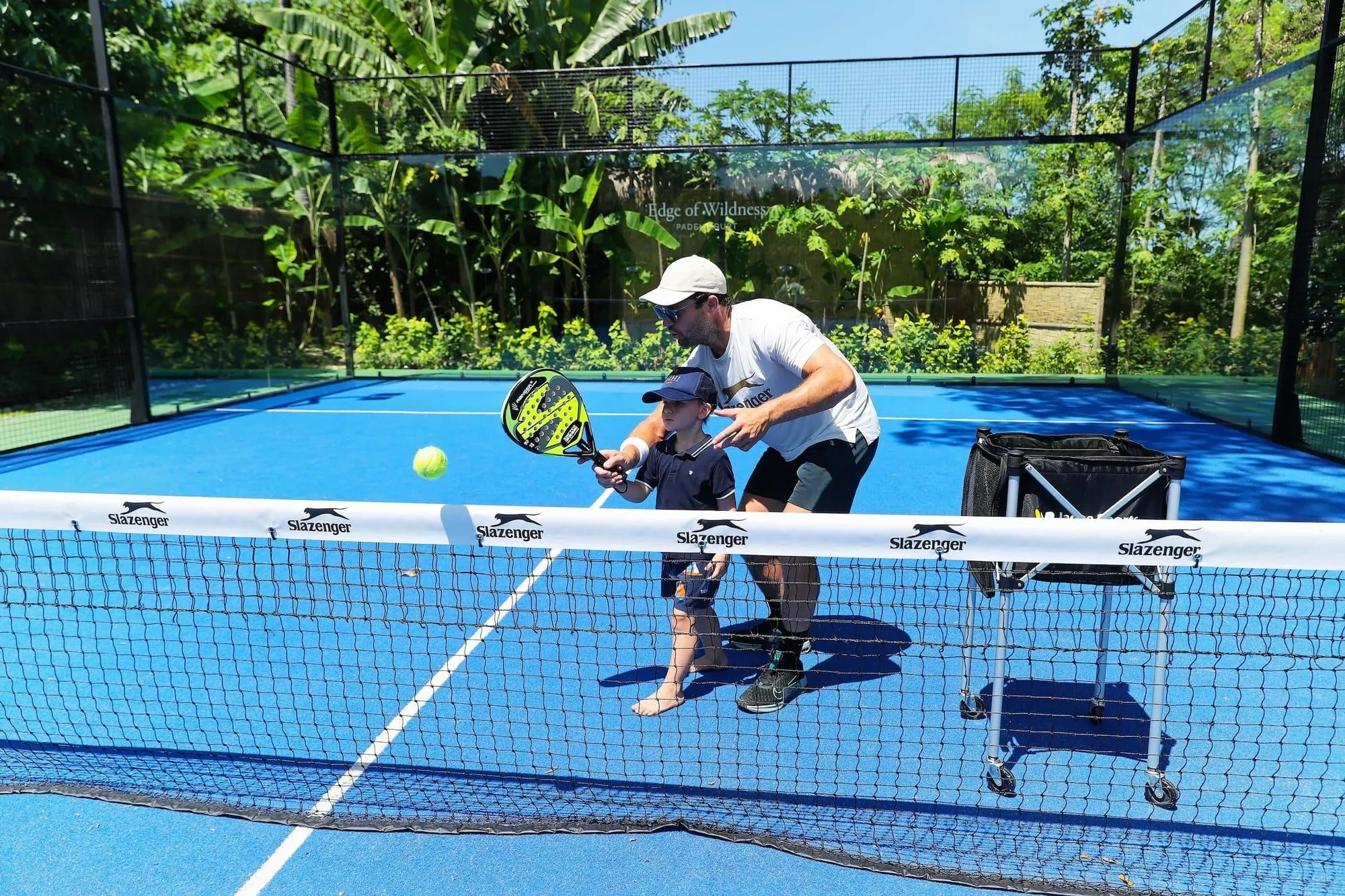 Coach guiding a child on a padel court