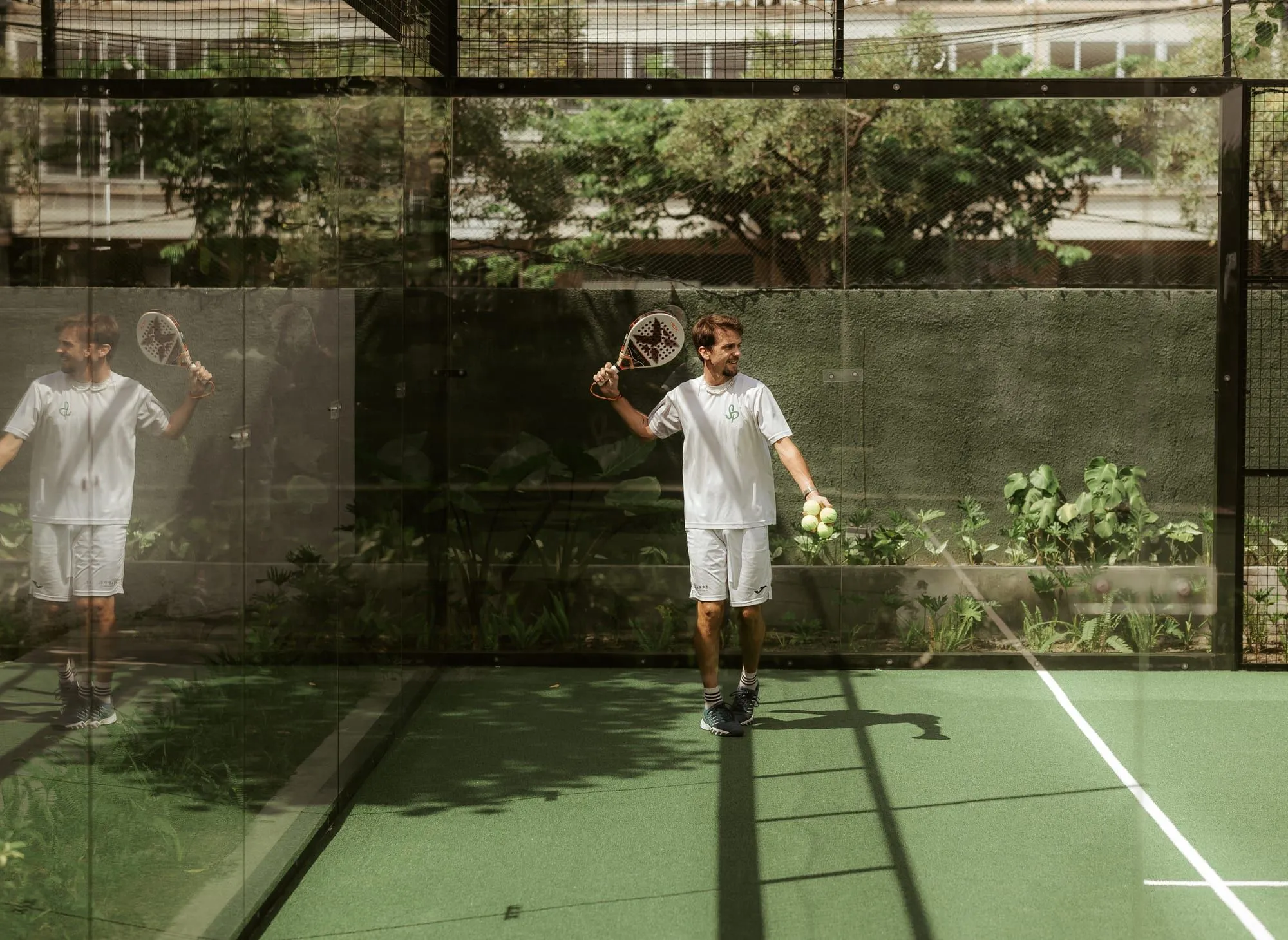 Padel player holding a racket and balls on court