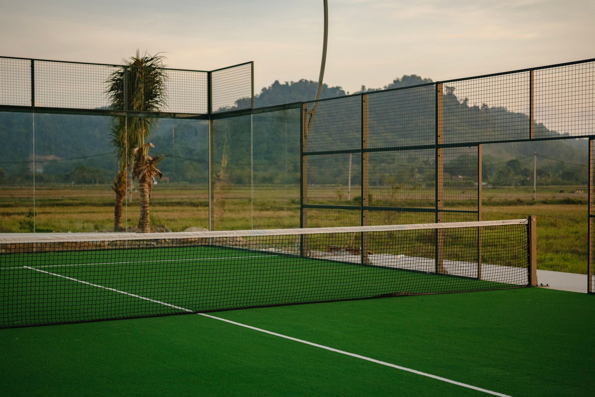 Outdoor padel court with glass walls looking onto open countryside
